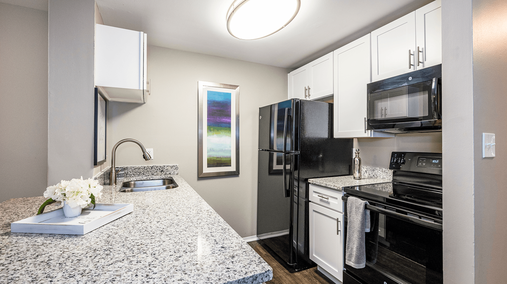 Apartments in Reynoldsburg, OH for Rent - The Oaks - Kitchen with Granite-Style Countertops, White Cabinets, and Black Appliances