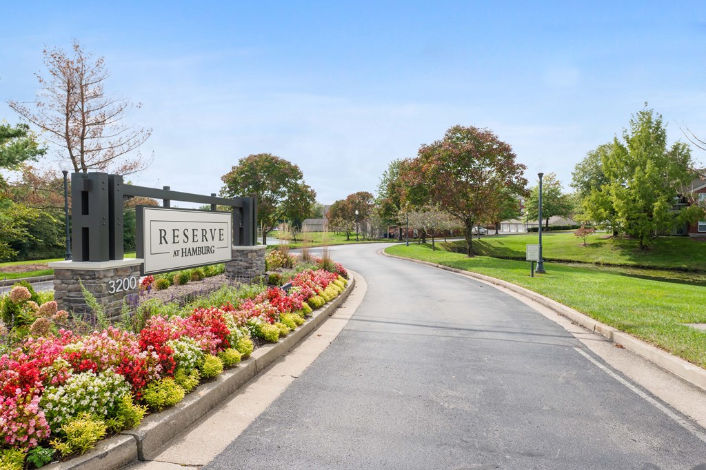 Reserve at Hamburg exterior sign surrounded by flowers, next to a paved driveway.