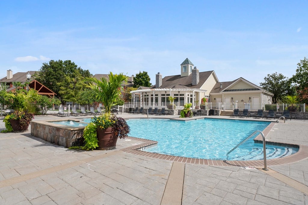 A resort-style swimming pool surrounded by chairs and lush greenery.