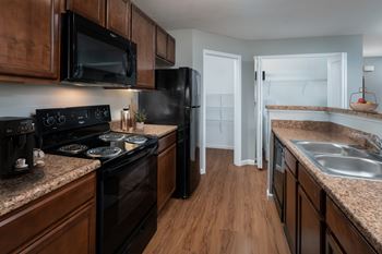 A kitchen with black appliances and wooden cabinets.