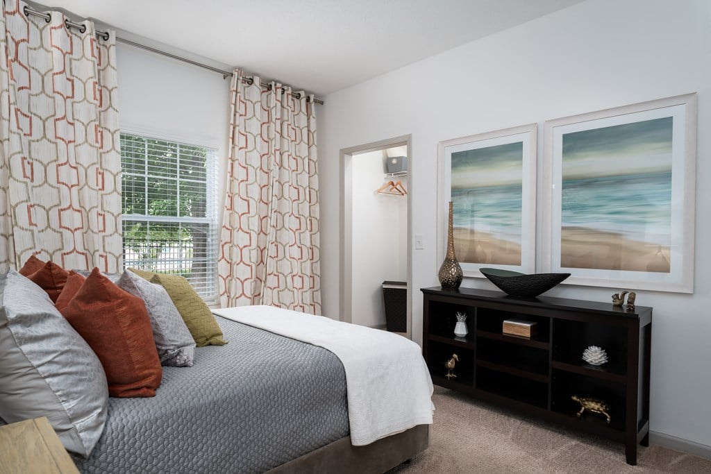 Furnished bedroom with plush carpeting, large bed, dresser, window, and modern decor at The Coleman in Canal Winchester, OH
