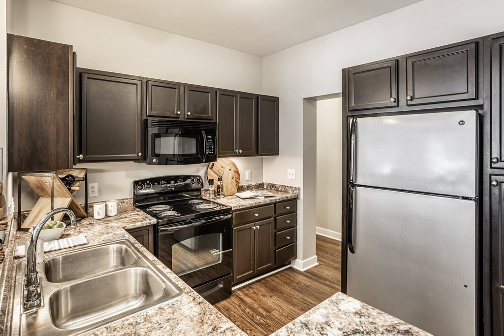 A kitchen with a sink, stove, and refrigerator.