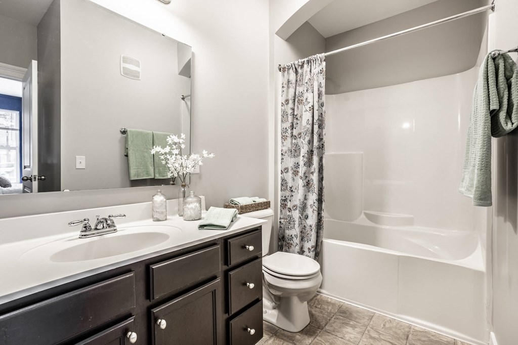 A white sink with a silver faucet is on a countertop with a mirror above it.
