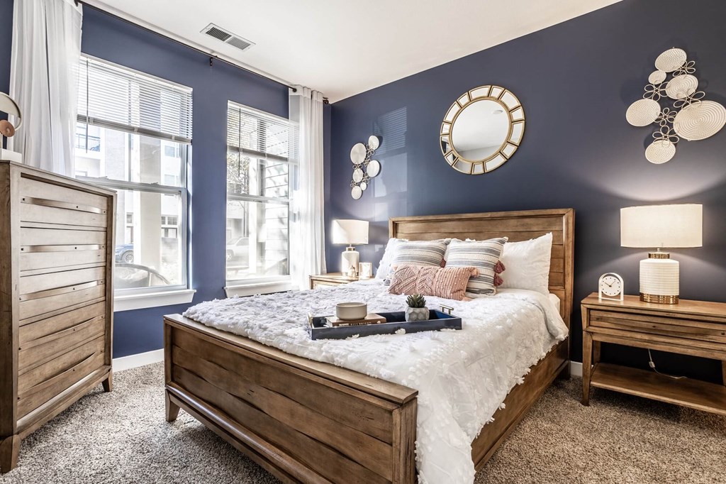 A bedroom with a large bed, a nightstand, and a window.