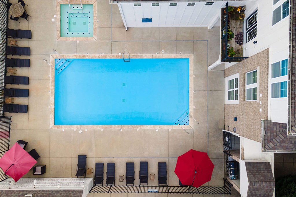 A large swimming pool surrounded by lounge chairs and umbrellas.