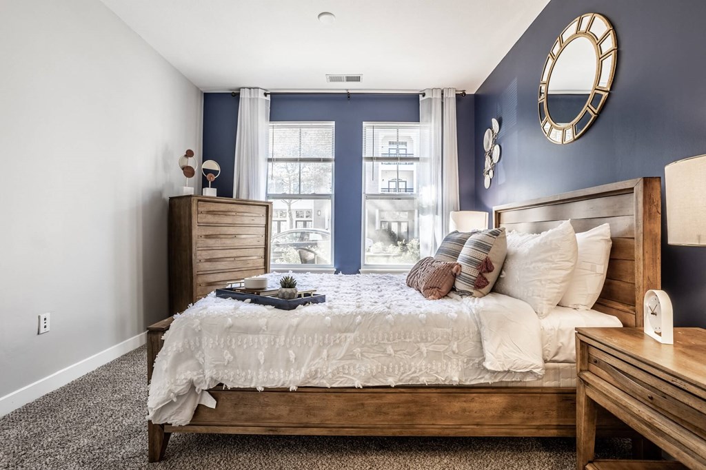 A bedroom with a large bed, a nightstand, and a window with curtains.