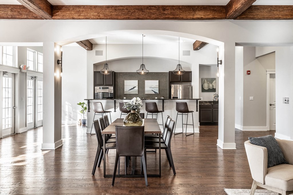 A dining room with a table set for six with a view of the kitchen.