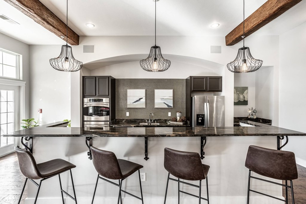 A modern kitchen with a black countertop and brown chairs.