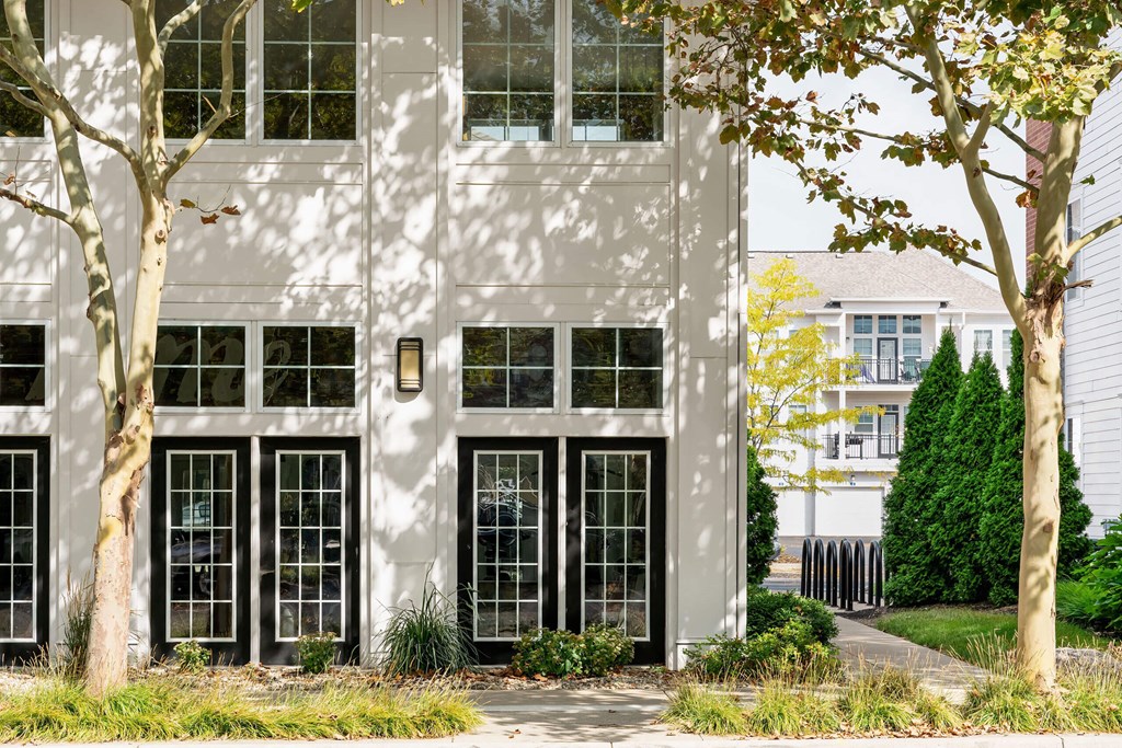 A white building with black windows and trees in front.