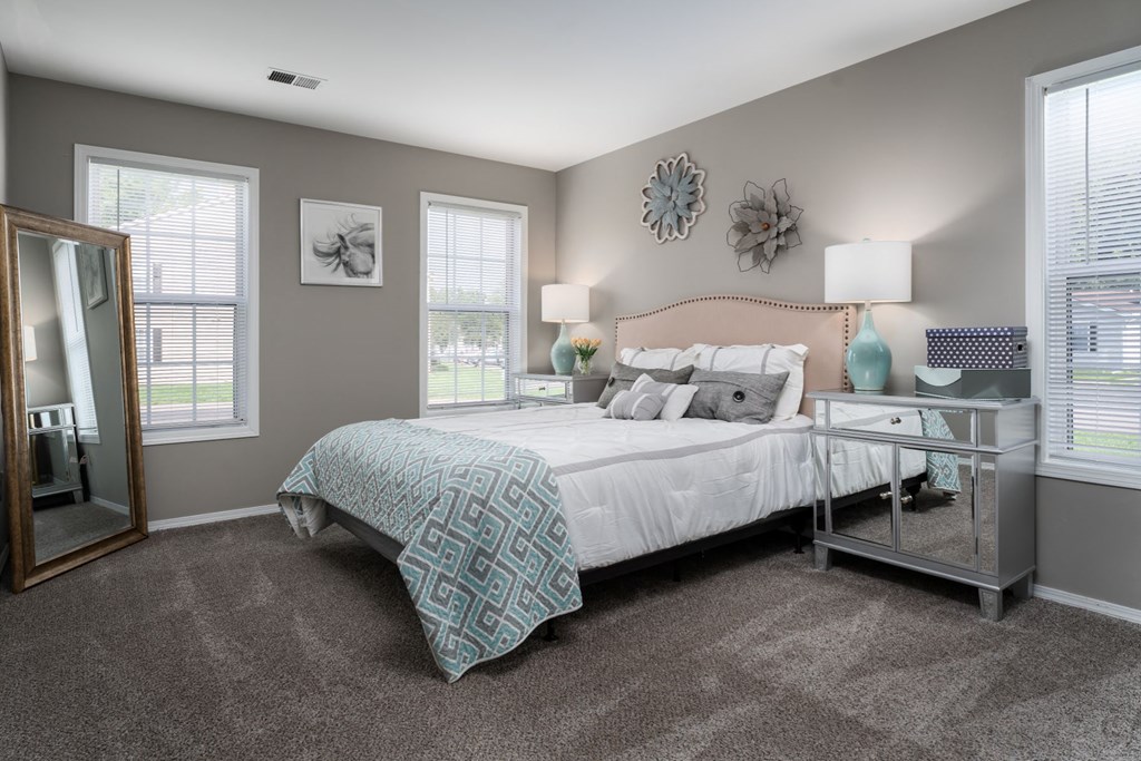 a bedroom with gray walls and a large bed with a white comforter