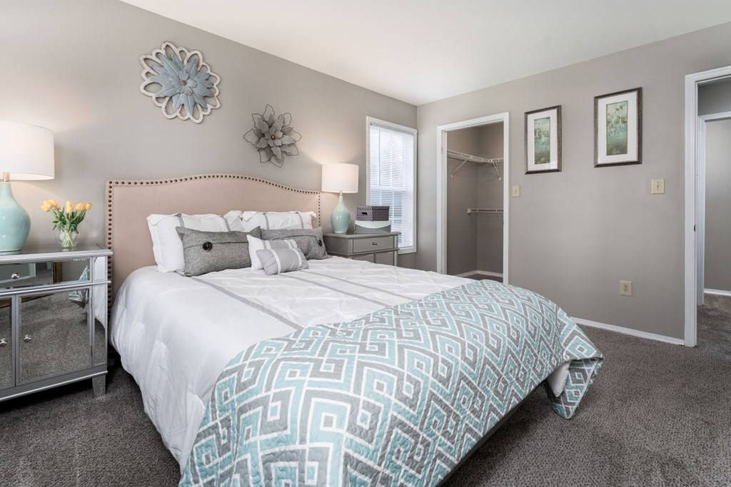a bedroom with grey walls and a large bed with a blue and white comforter