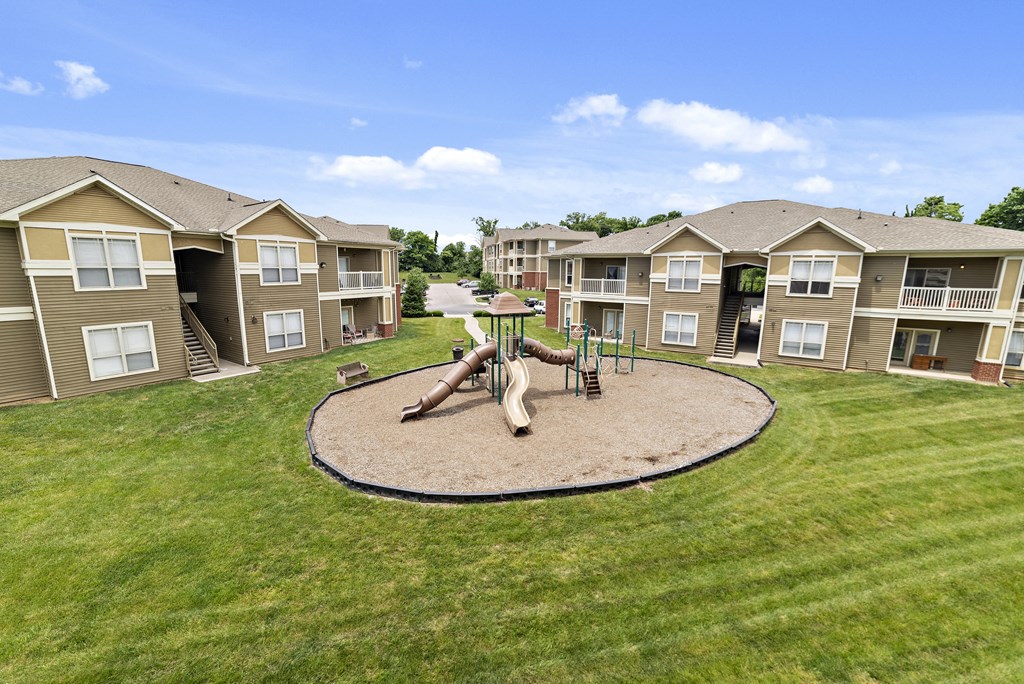 Apartments in Florence, KY for Rent - Trellises - Playground with Slides and Climbing Equipment, Surrounded by Lush Grass and Apartment Buildings.