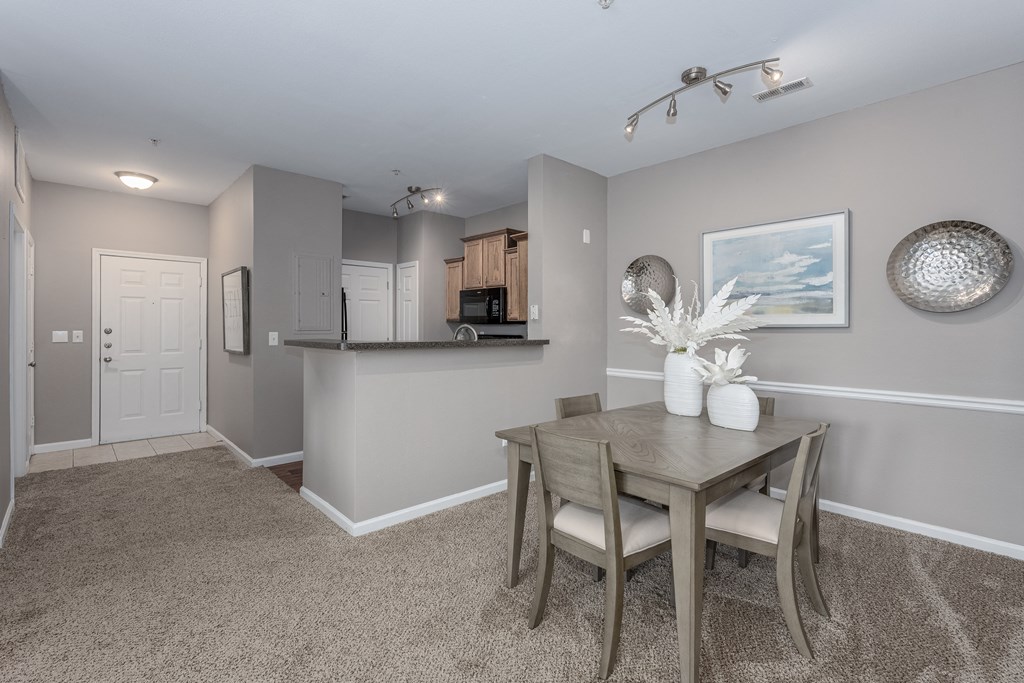 a dining area with a table and chairs and a kitchen in the background