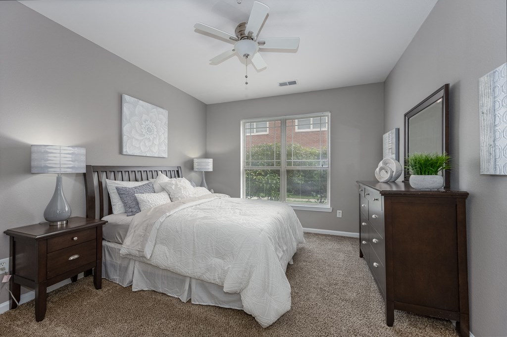 Three BR Apartments in Florence, KY - Trellises - Furnished Bedroom with Bed, Wooden Nightstand and Dresser, Carpet Flooring, Window, and Ceiling Fan
