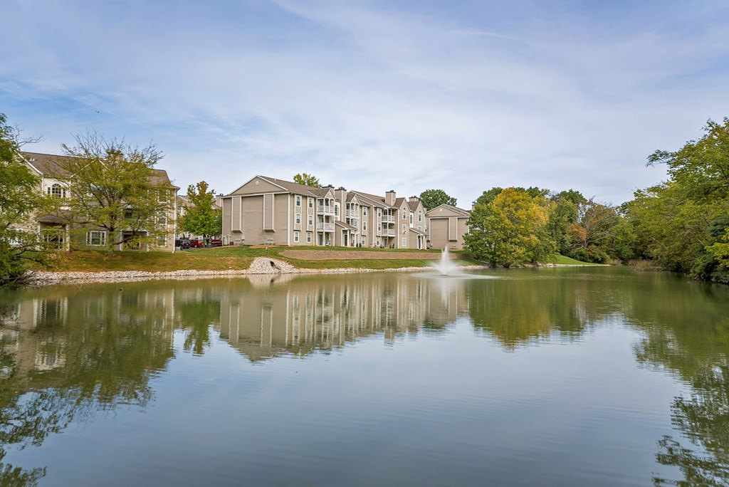 a lake with a fountain in front of a building
