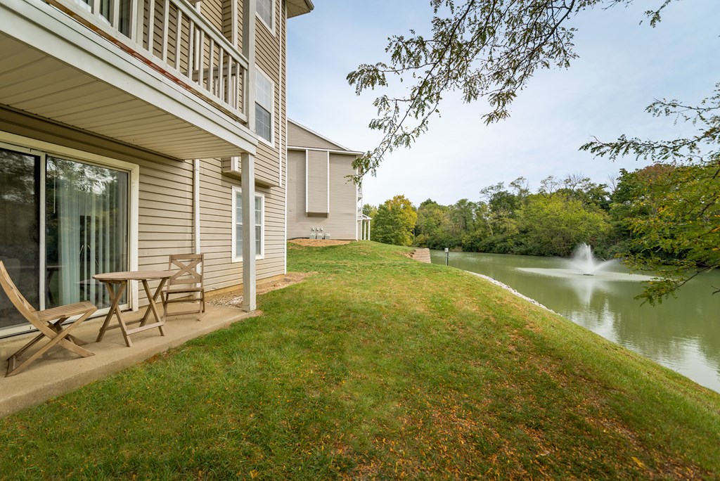 Charming patio area with a table and two chairs beside a serene water feature