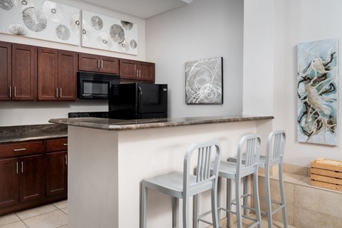 a kitchen with a counter with three chairs and a microwave