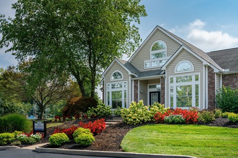 Windridge leasing office exterior with a sign, plants, and large trees.