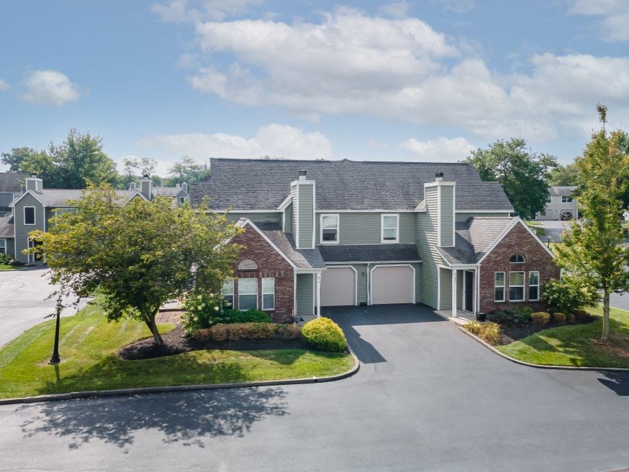 a large house with a driveway and trees in front of it