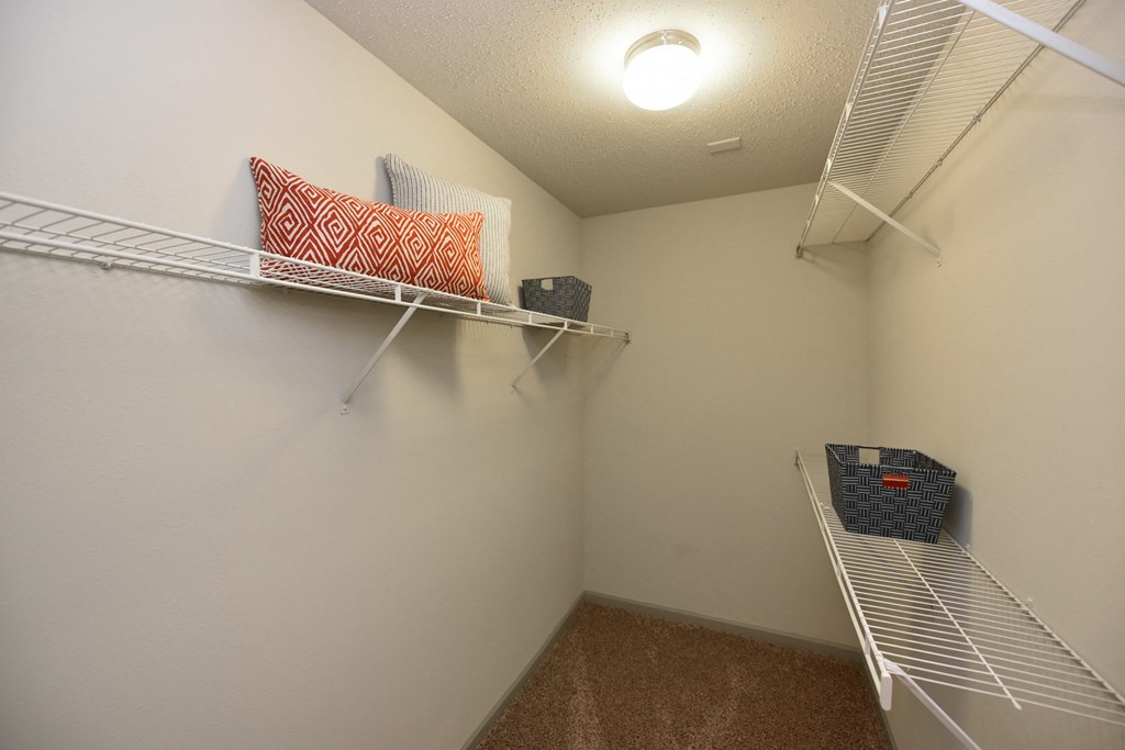 a spacious walk in closet with two shelves and two pillows