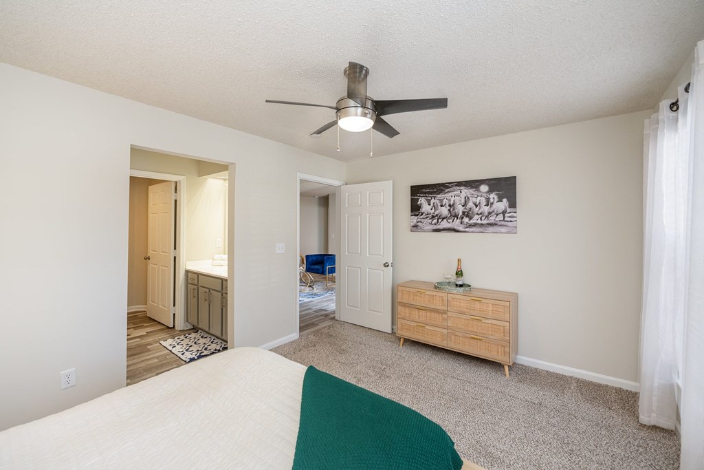 A furnished bedroom with carpeted flooring and a bathroom.