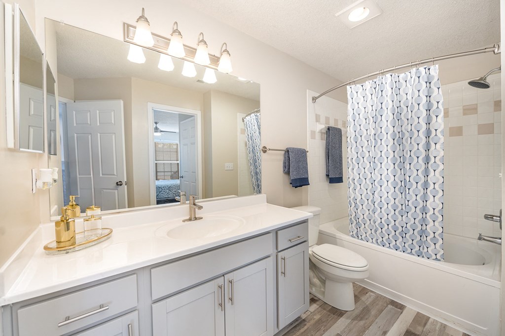 A bathroom at Reserve at Hamburg with a vanity and a large mirror, white furniture, and hardwood-style floors.