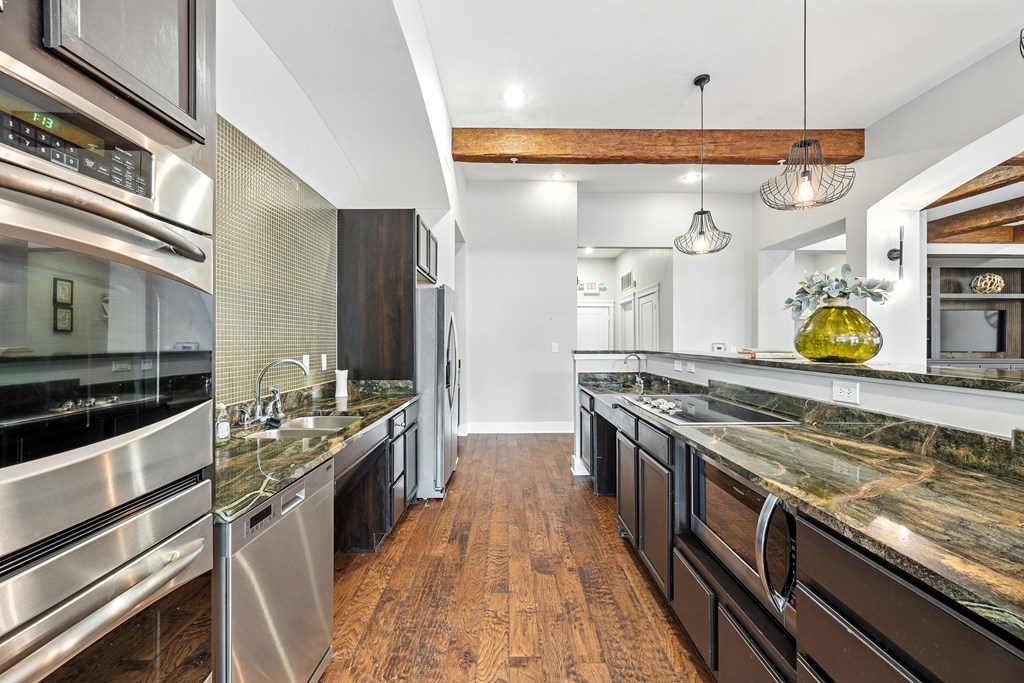 A modern kitchen with dark wood floors and stainless steel appliances.