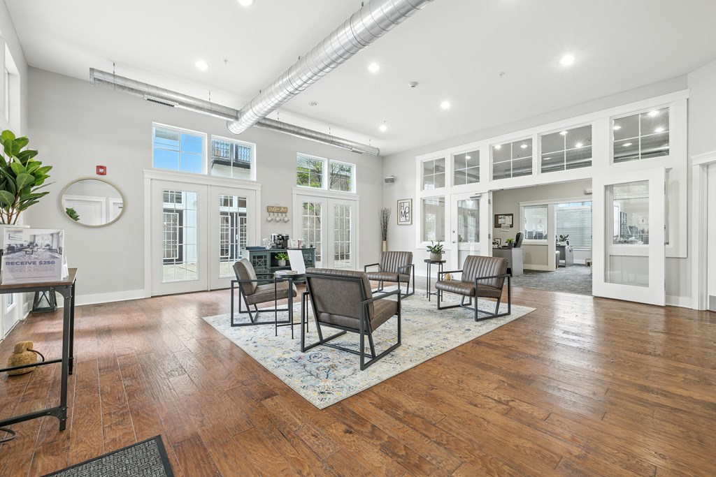 A spacious room with wooden floors and a variety of seating options.