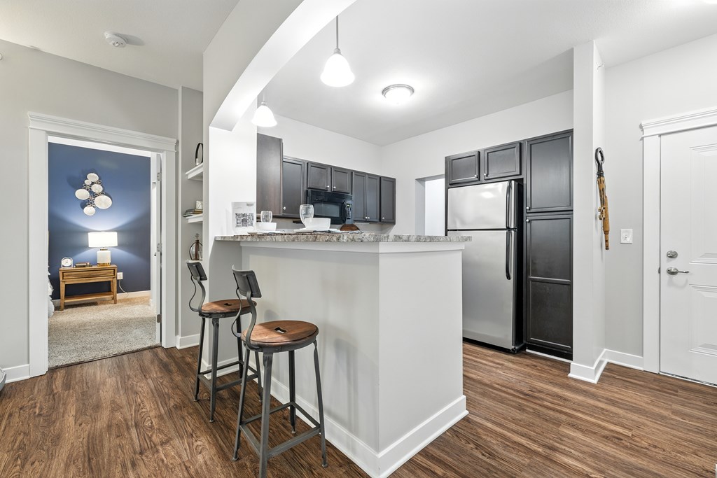 A kitchen with a white island and dark wood floors.
