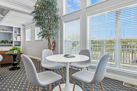 A dining room with a white table and grey chairs.