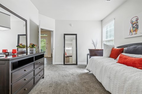 A bedroom with a large bed and a dresser with a mirror above it.