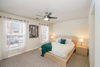 A bedroom with a bed, nightstands, and a ceiling fan.