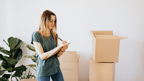 A woman is standing in front of cardboard boxes.