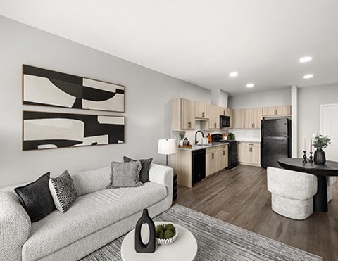 A modern living room with a grey couch and a black and white abstract painting on the wall.