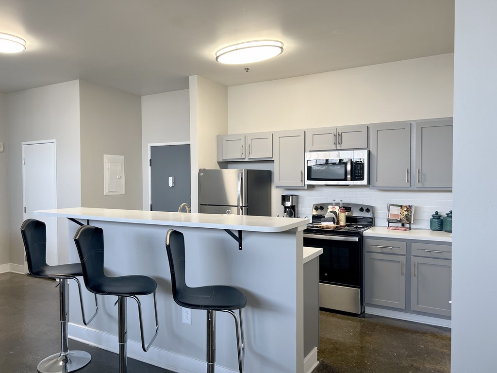 A kitchen with white cabinets and black bar stools.
