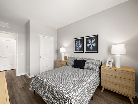 A bedroom with a patterned bedspread and two lamps on the nightstand.