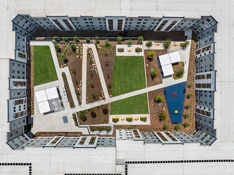 A large courtyard surrounded by buildings with a grassy area and a pool.