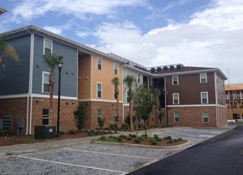 A multi-story apartment building with a parking lot in front.