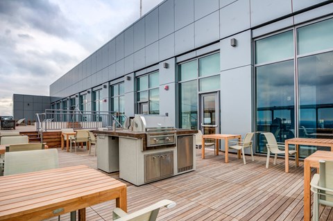 a patio with tables and chairs and a grill on the side of a building