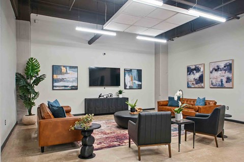 A modern living room with a brown leather couch, a black armchair, and a wooden coffee table.