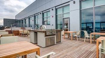 a patio with a grill and tables and chairs
