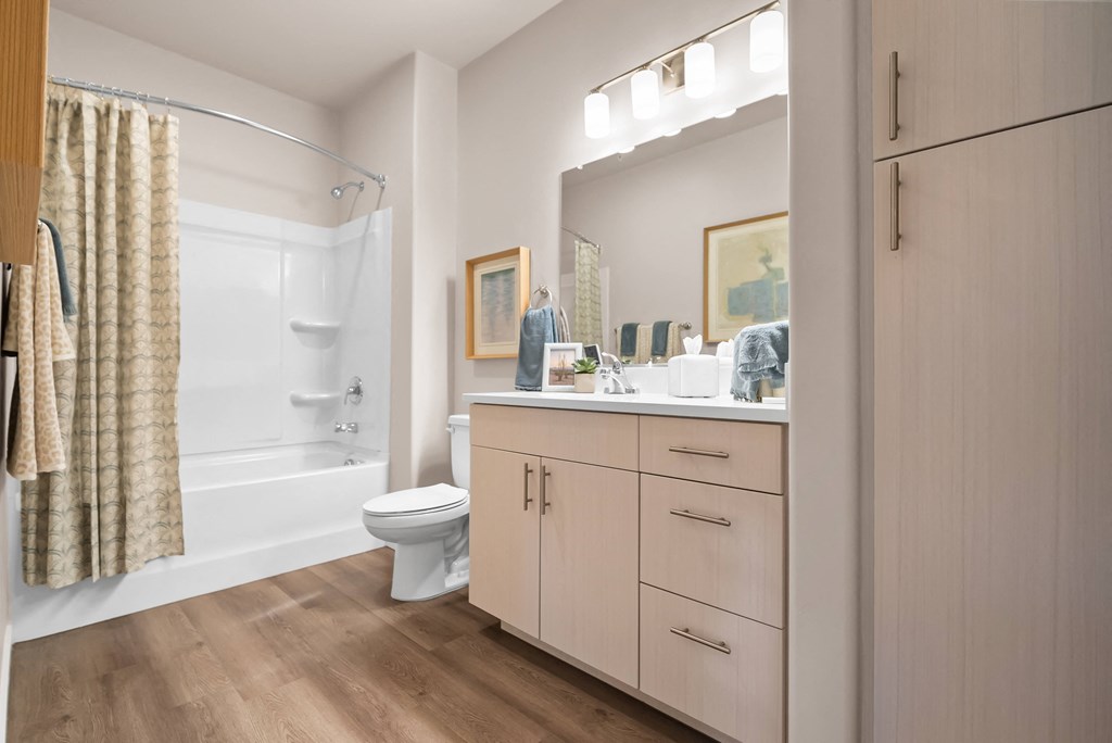 A bathroom with a toilet, sink, and cabinets.