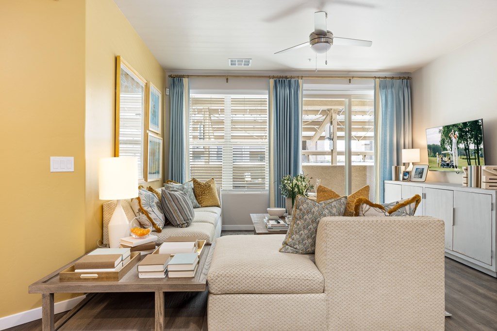 A living room with a beige sofa, a wooden coffee table, and a ceiling fan.