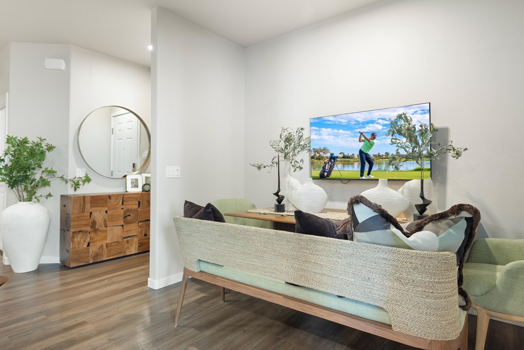 A bedroom with a bed, a mirror, a painting, and a plant.