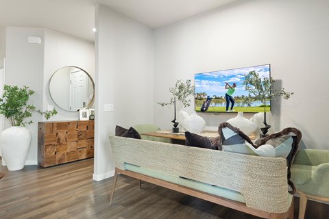 A bedroom with a bed, a mirror, a painting, and a plant.