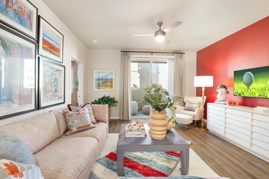 A living room with a beige couch, a coffee table, and a ceiling fan.
