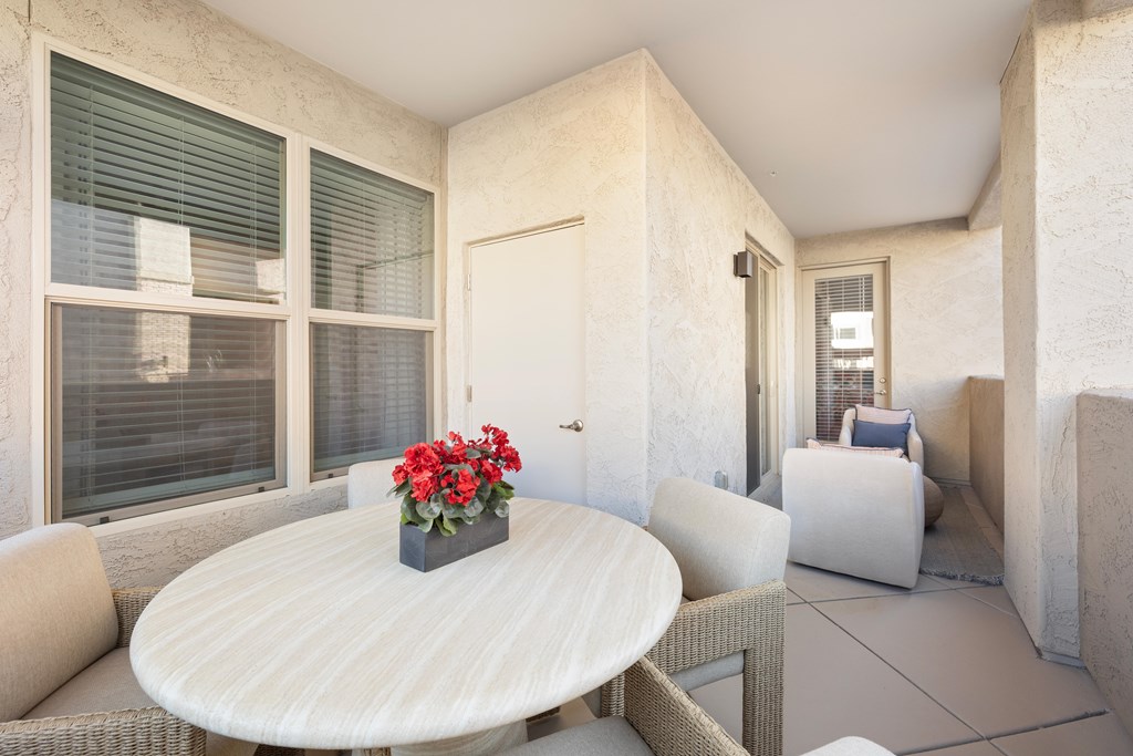 A white table with a vase of red flowers on it.