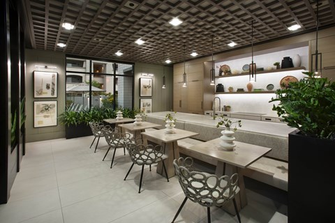 A restaurant with tables and chairs and a plant in a planter.