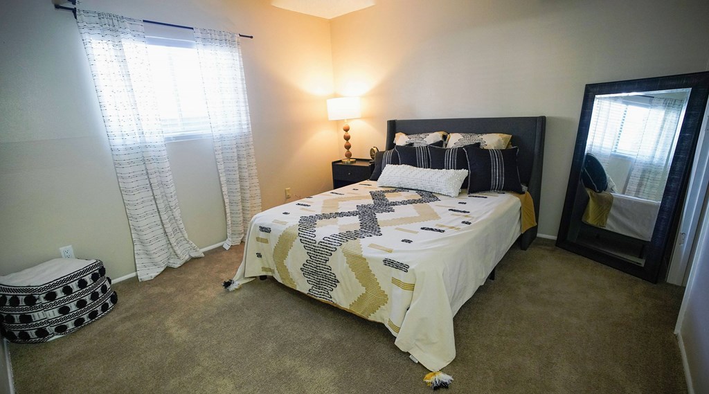 A bedroom with a bed, lamp, and window.