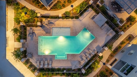 A swimming pool surrounded by a patio and a garden.
